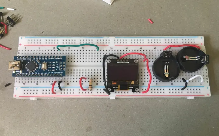 Photo of CEL wallet prototype V1: an Arduino Nano, a small OLED screen, and two coin-cell holders wired on a breadboard.