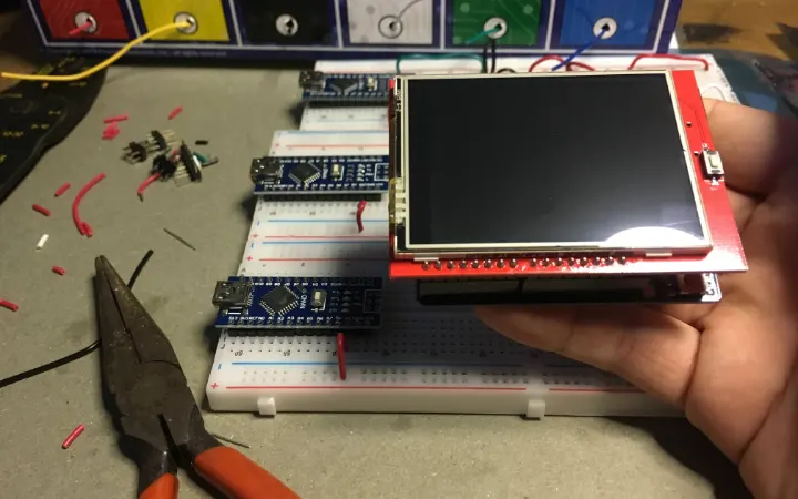 Photo of CEL wallet prototype V2: a hand holding a 2.5-inch touch screen mounted on an Arduino board, above a breadboard.